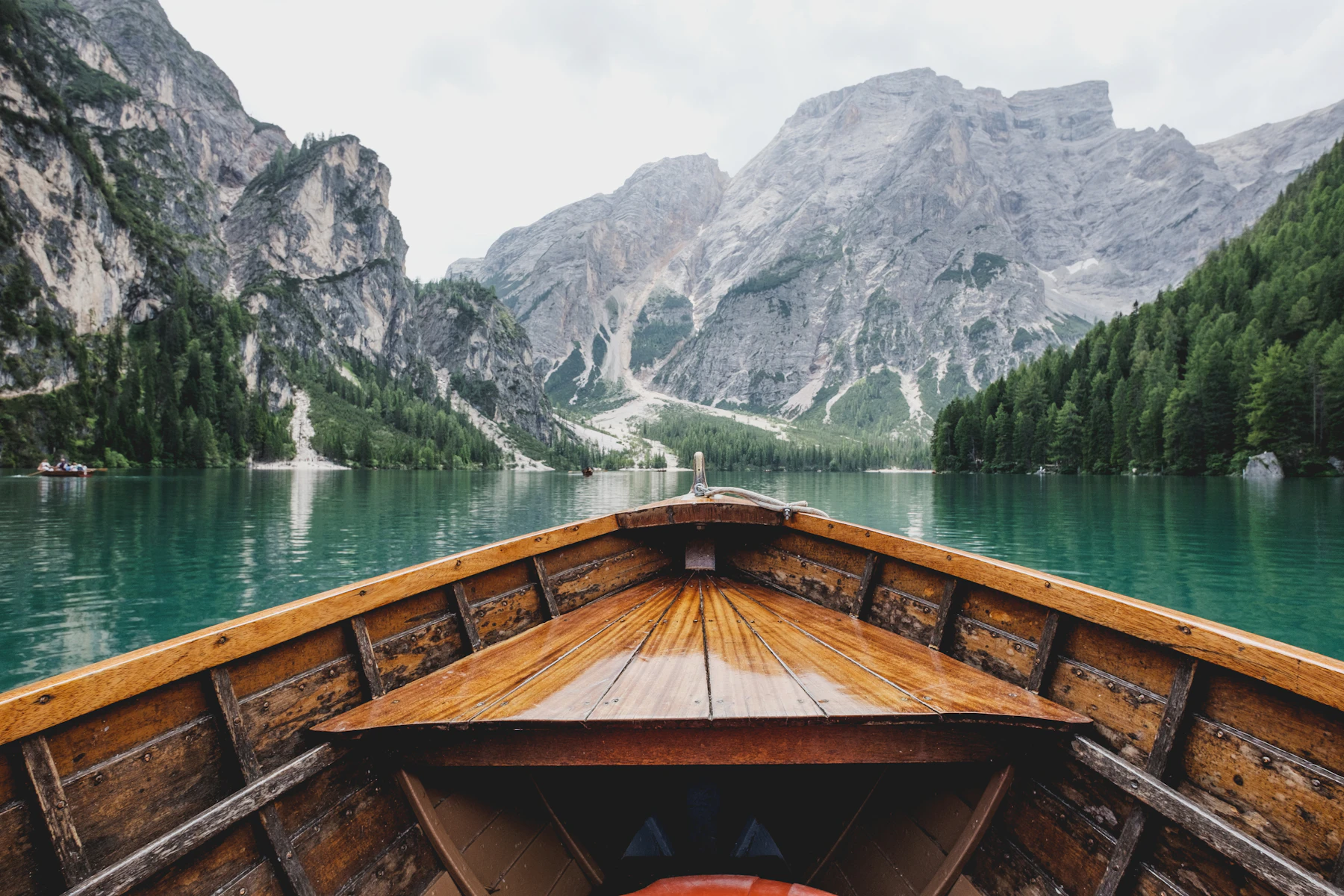 The bow of a wooden rowing boat on a turquoise alpine lake below limestone peaks