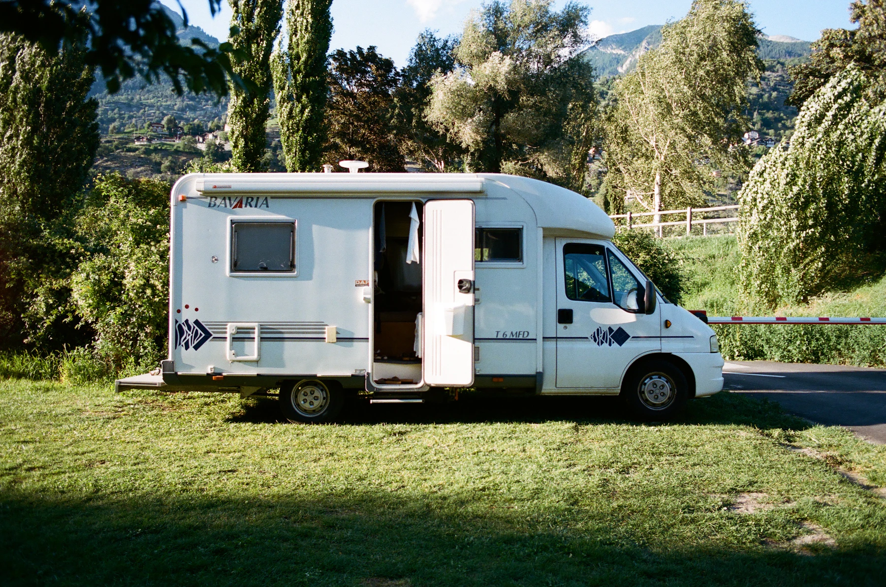 A white motorhome on a grass pitch among trees